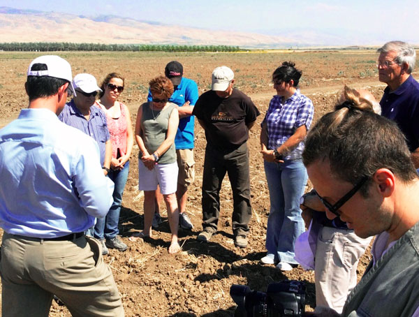 Zion Board Members and Staff Praying Over Possible Well Drill Site. The site is near Kibbutz Sde Eliyahu in the fertile Beit Shean Valley. The kibbutz grows a variety of crops on the land.